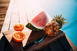 Fruit tray on a wooden board displayed by the pool on a sunny day