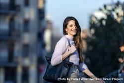 Long haired smiling woman with handbag outside at dusk 5RVrA1