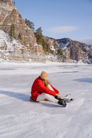 Woman sitting on snow and changing boots