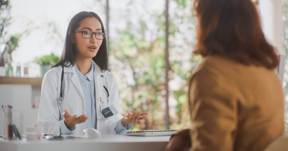 Portrait of an Asian Healthcare Professional Listening to a Mature Female Patient Before Prescribing Treatment for Her Medical Condition During a Consultation in a Modern Health Clinic