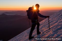 Silhouette of person climbing snow covered steep during sunset 4mGLX0