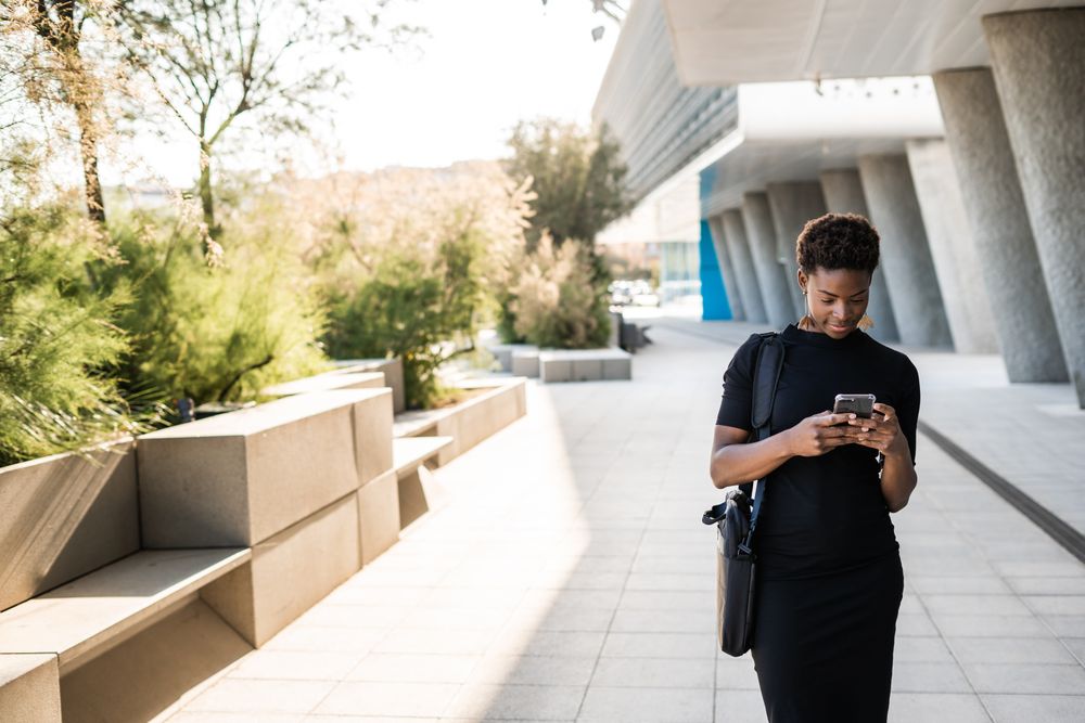 Concentrated female using mobile near urban building