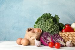 Wicker basket and vegetables on wooden background, copy space