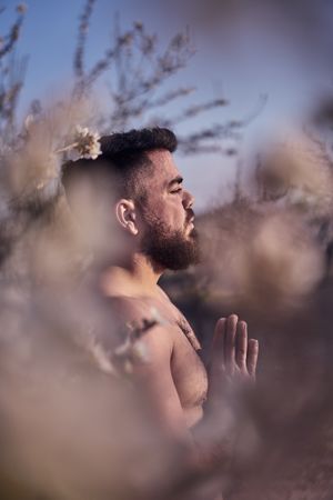 Shirtless man meditating in spring garden
