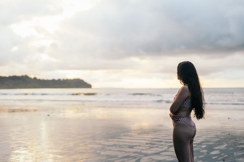 Young woman watching sunset standing on the beach