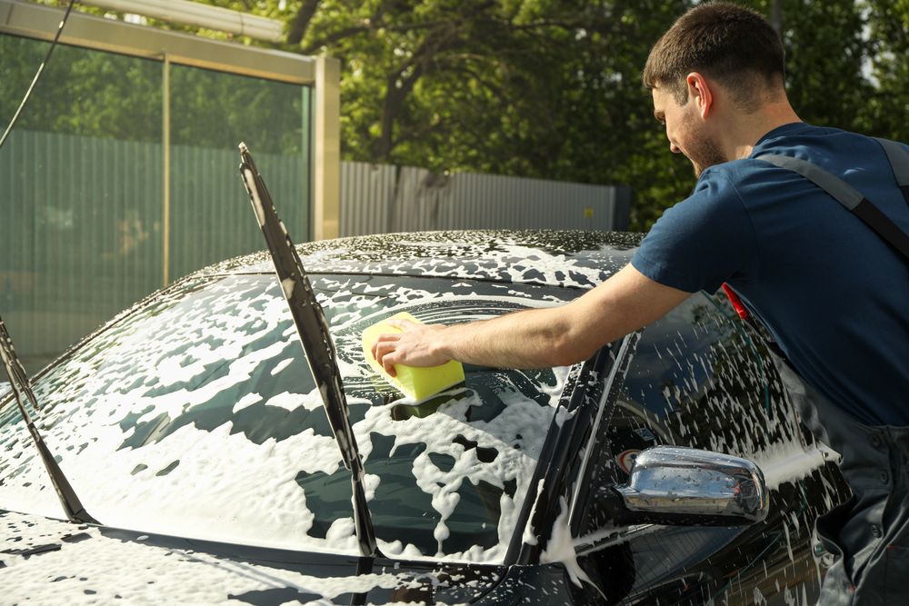 Man wipes the car with a sponge. Car wash. Clear car concept