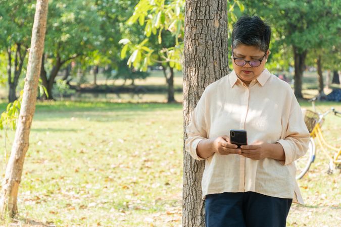 Mature Asian woman checking smart phone in park