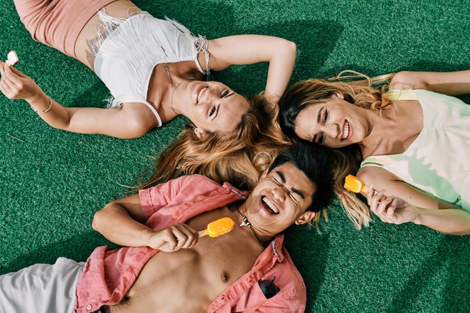 a group of young people having a good time and eating ice-cream lying on grass