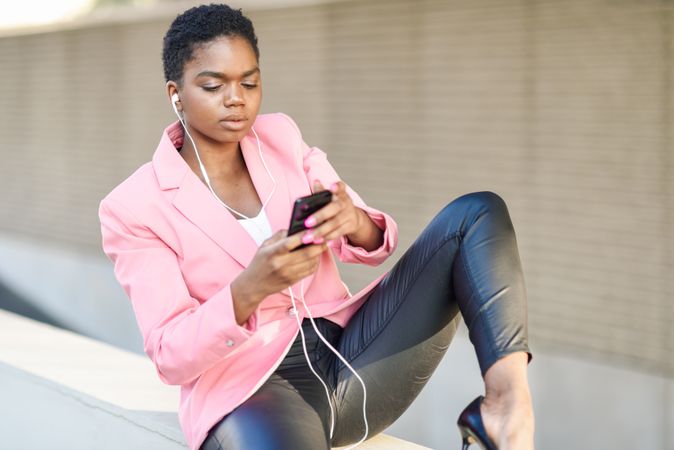 Female wearing suit with pink jacket checking cell phone