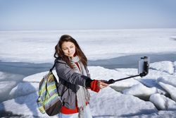 Female traveler outdoors at icy landscape using monopod to make