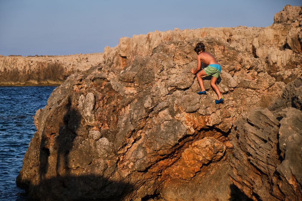 Boy scrambling on stony coast