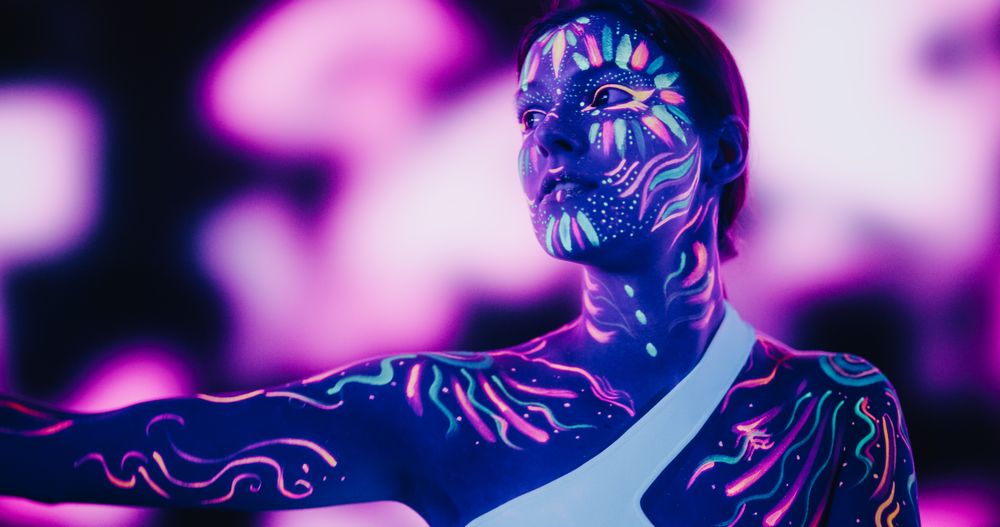 Woman Embodies Modern Dance with Colorful Neon Paint on Her Body in a Dark Studio