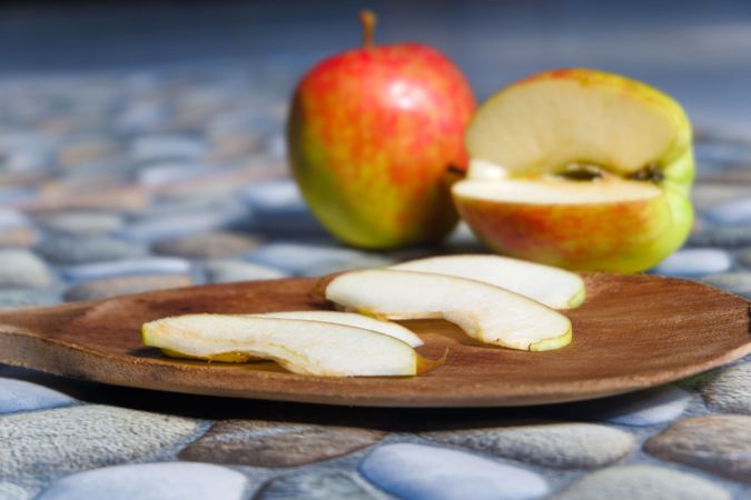 photos of apples in various styles, some are still intact, some are cut with a stone background