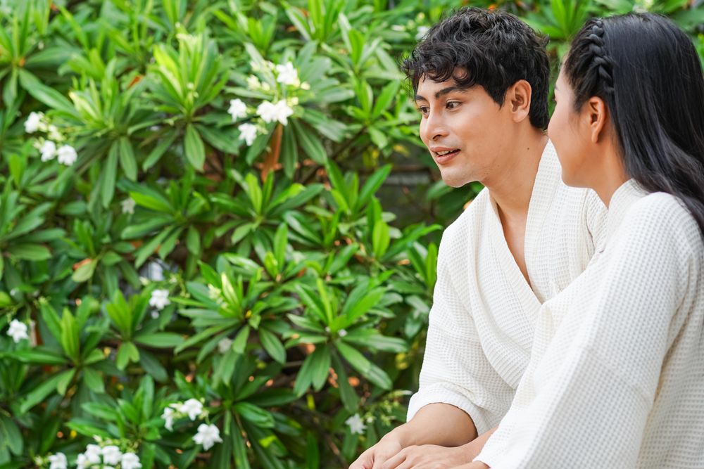 Asian couple in hotel bathrobe standing together at balcony