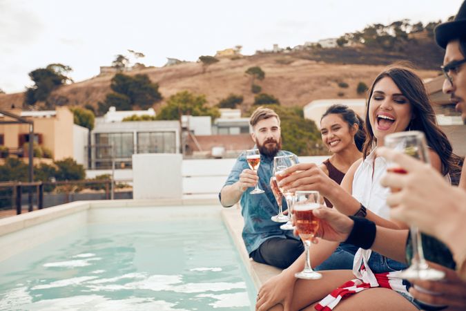 Multi-ethnic friends enjoying and toasting drinks during a rooftop party