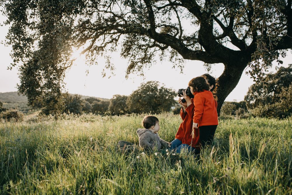 Young child looking through her mother’s camera in a park