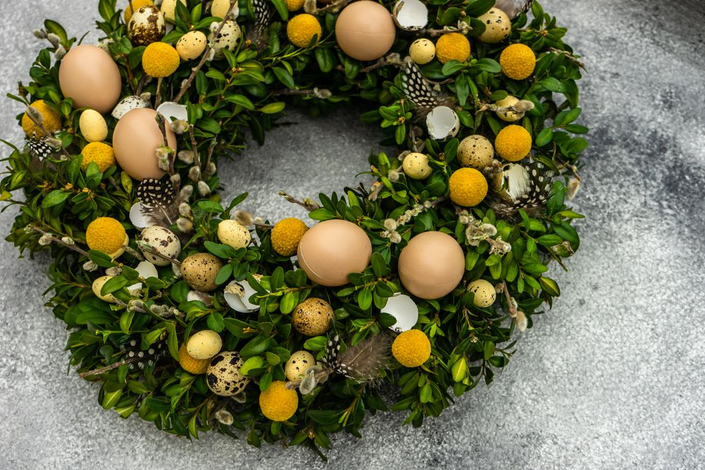 Top view Easter card concept with fresh wreath with decorative eggs and feathers