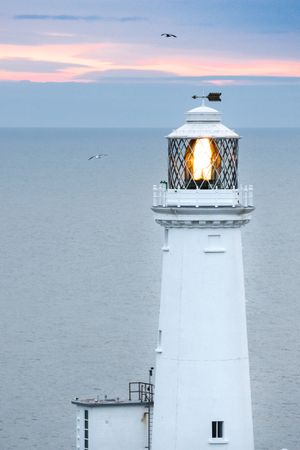 Lighthouse with lighting lamp at sunset