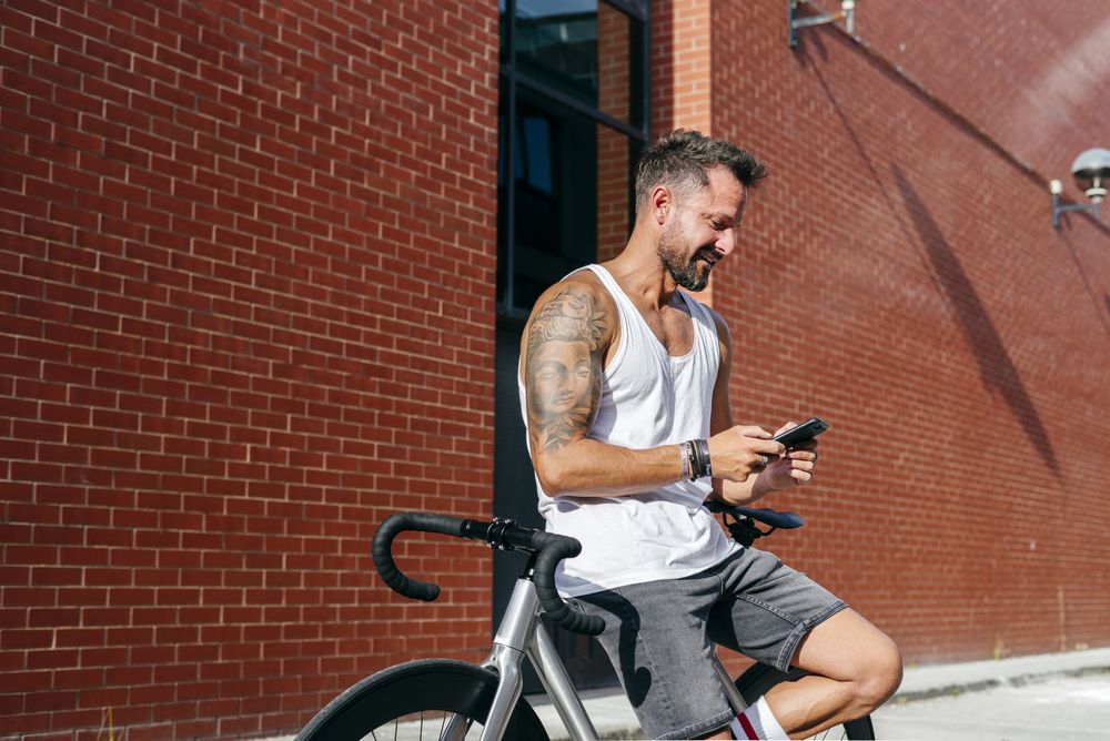 Sportive man with bicycle using phone
