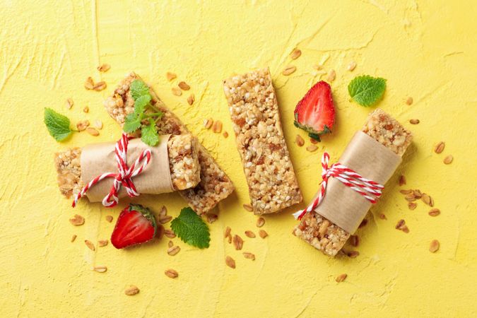 Tasty granola bars on yellow background, top view