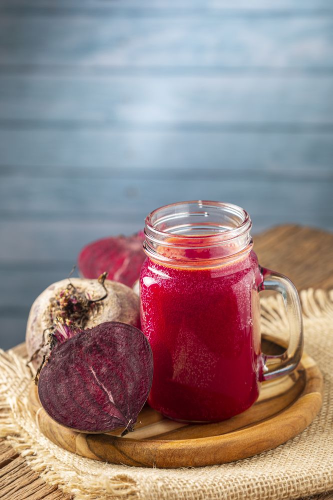 Red beet juice in a glass cup on the wooden table.