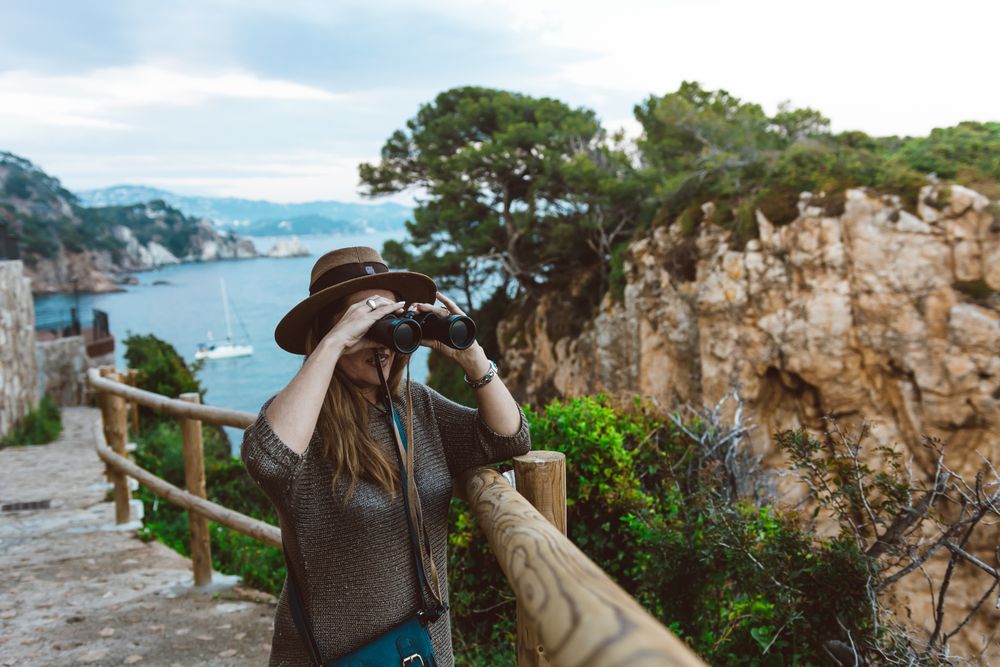 Woman with binocular on coastal walkway