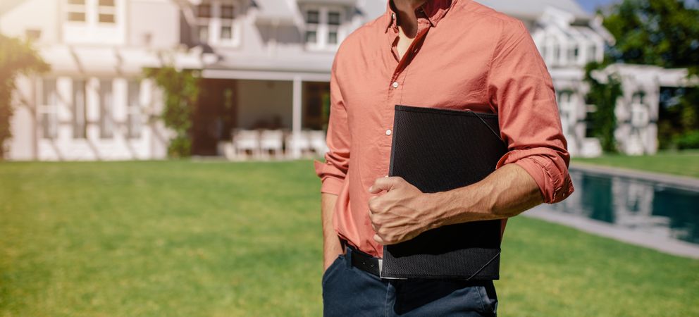 Man holding folder of documents in an affluent backyard