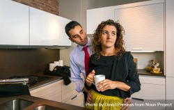 Businessman embracing annoyed curly woman while holding cup of coffee in the kitchen 4Zy895