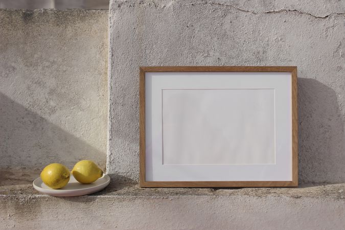 Blank horizontal wooden picture frame mockup against old textured shabby wall.