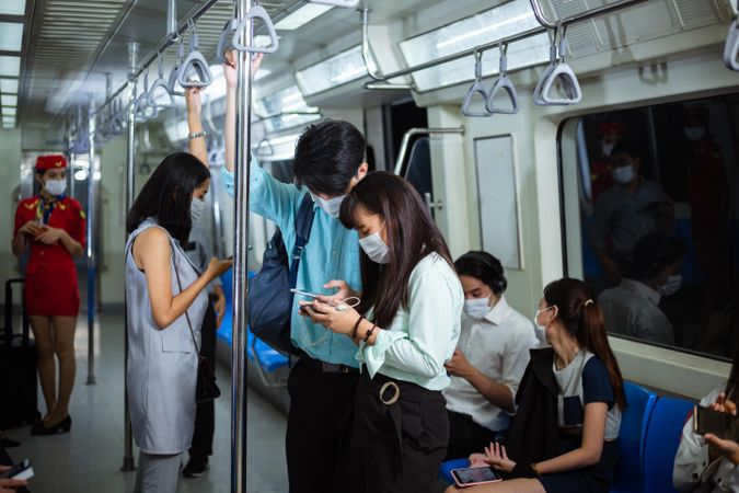 Group of passengers sitting and standing in a subway train