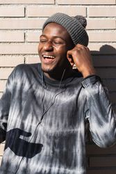 Black man enjoying music from earphones while dancing outdoors