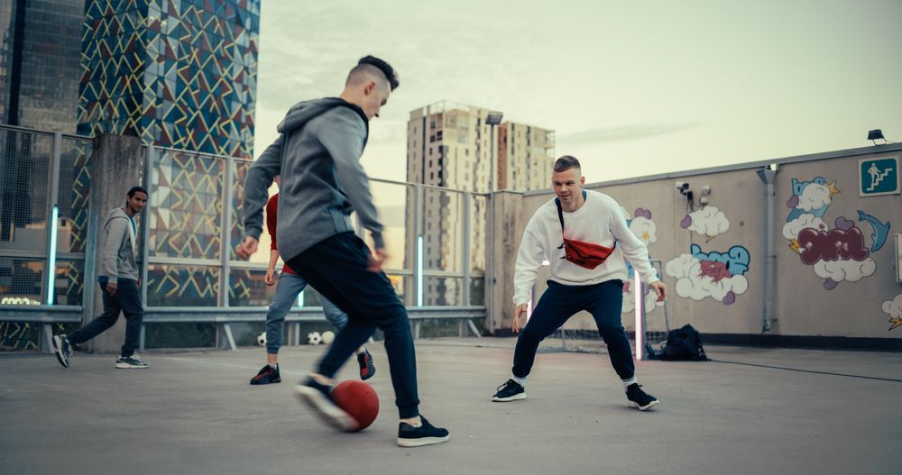 Multiethnic Diverse Friends Playing Soccer Outside on Rooftop Urban City Location.