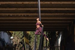 Sporty woman doing yoga with aerial silks in city