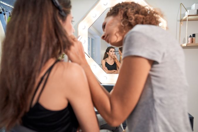 Visagiste applying makeup on woman
