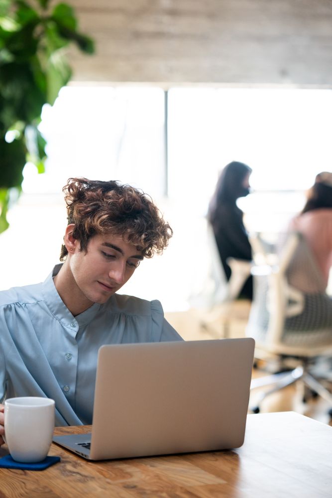 Nonbinary person working on laptop on wooden table