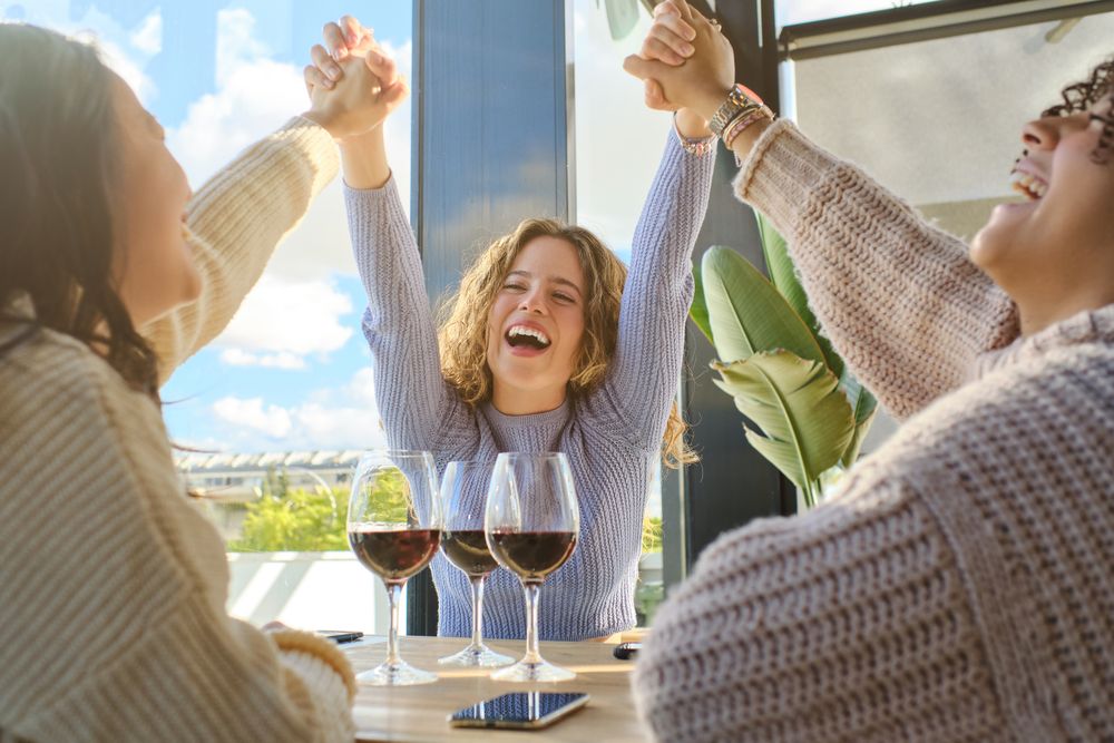 Laughing girlfriends at restaurant with wine