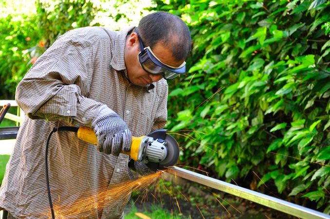 Man with goggle cutting a metallic rod