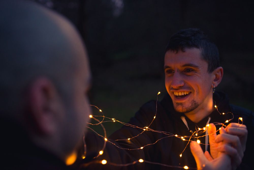 Men unwrapping fairy lights in forest at night