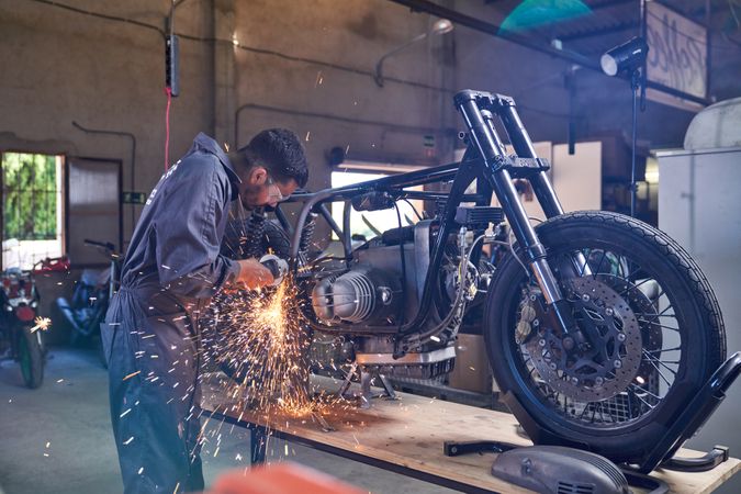 Mechanic using angle grinder while repairing motorcycle