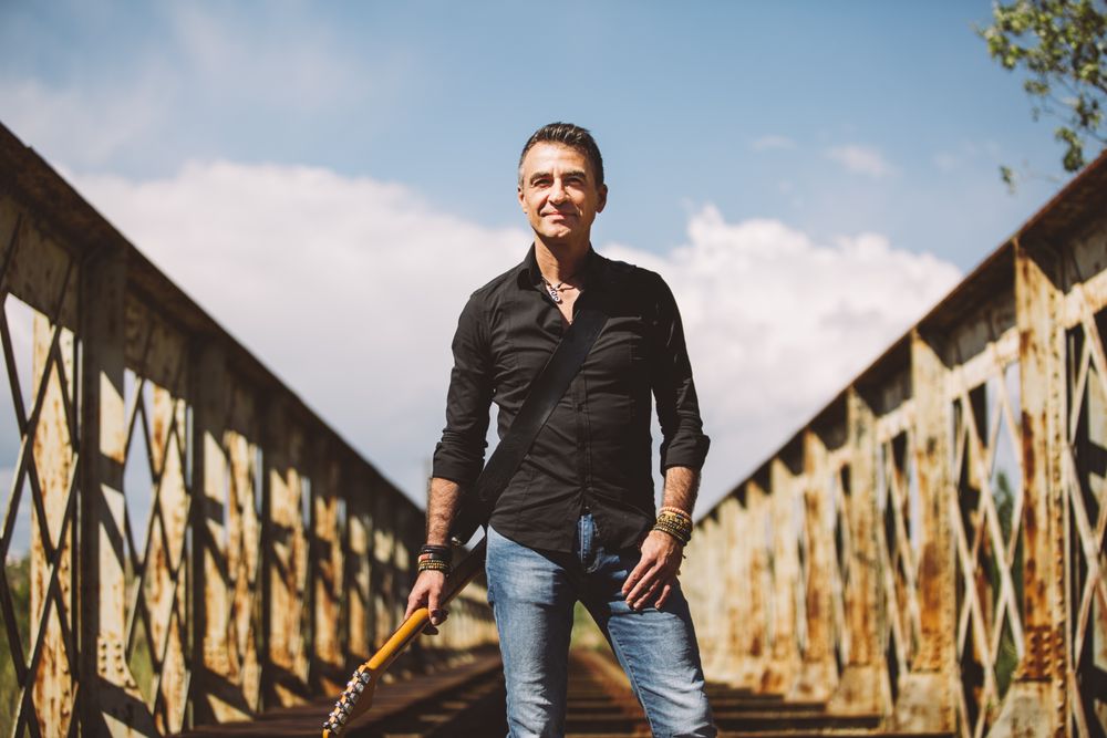 Man with guitar standing on bridge