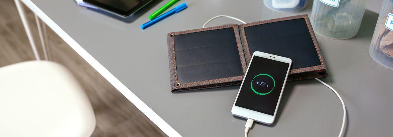Mobile phone charging with portable solar panel bins over desk in classroom