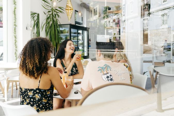 Diverse friends with smoothies sitting in cafe