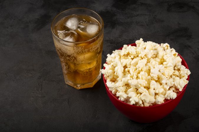 Bowl with salted popcorn and soda on the table.