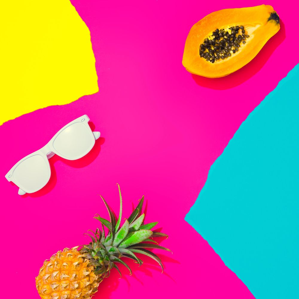 Pineapple, papaya and sunglasses on pattern of ripped paper in vivid colors
