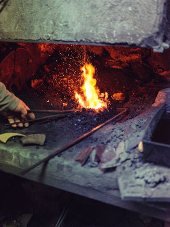 Man heating metal for forging in fire