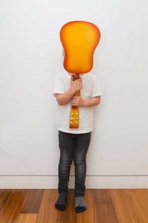 Young blonde boy playing toy guitar