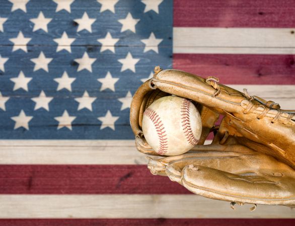 Weathered baseball mitt and ball with faded boards painted in American USA flag colors