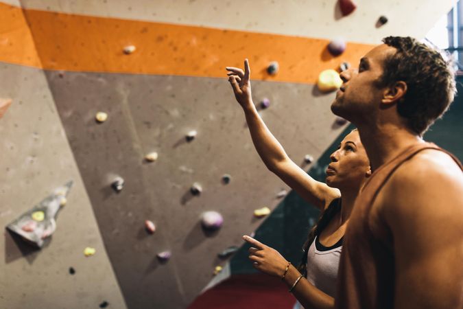 Female instructor giving instructions to man on wall climbing