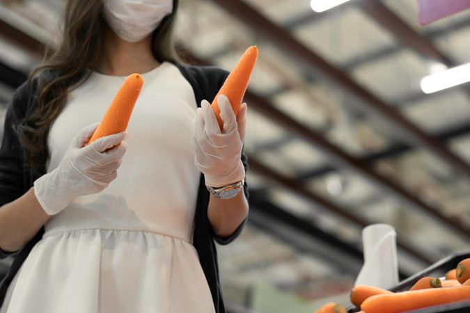 Woman in rubber gloves choosing carrots in super market