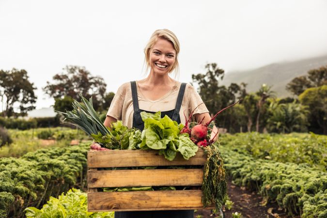 Happy young woman smiling at the camera while standing in her vegetable garden